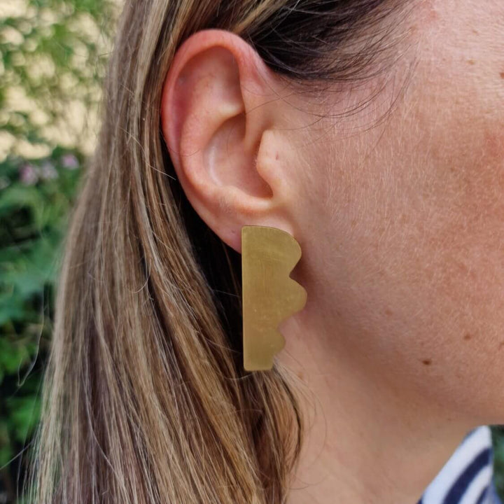 Dream I statement earrings by Bold Lines Jewellery are shown on a woman's ear with trees in the background.