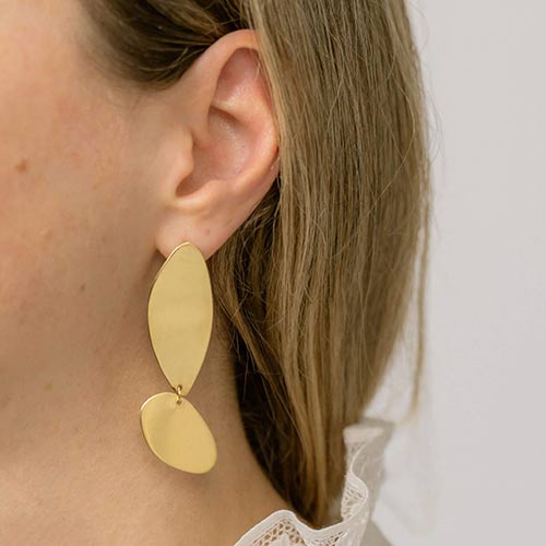 A woman in a white shirt showing the asymmetrical Fluidity earrings by  Bold Lines Jewellery.