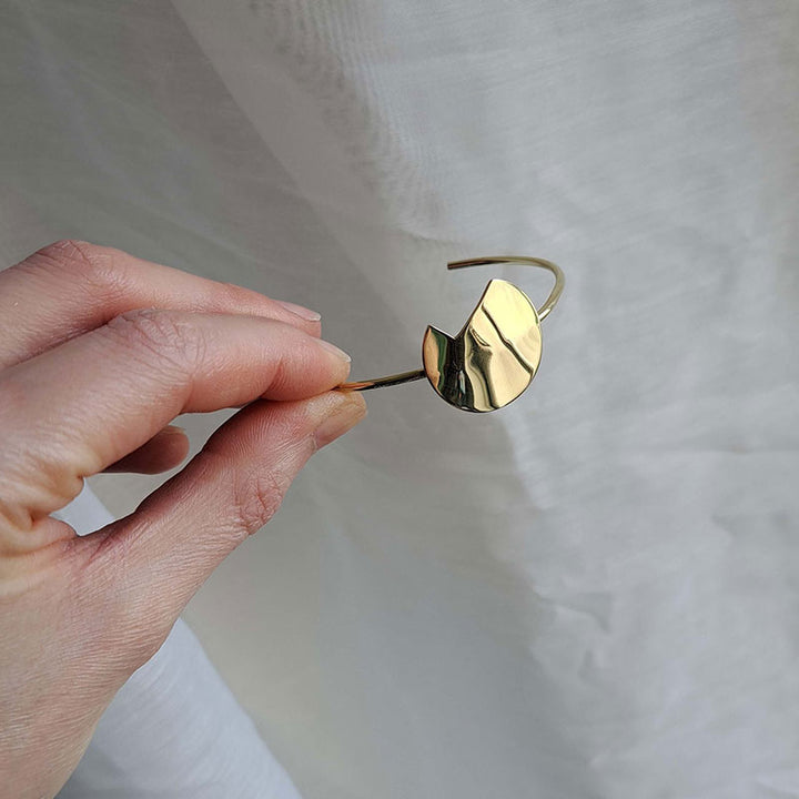 A shot focused on the hand holding the Gold Bold Balance bracelet by Bold Lines Jewellery.