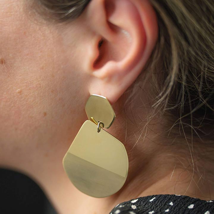 Reflection statement earrings designed by Bold Lines Jewellery show a woman's ear wearing a black and white dot collar.