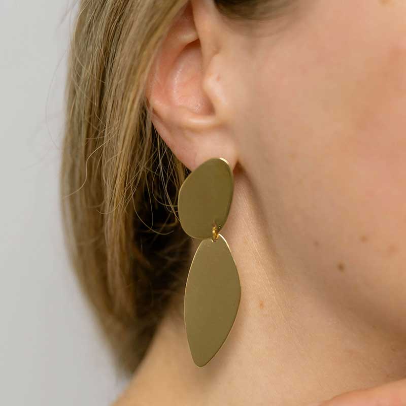 A woman in a white shirt showing the asymmetrical Fluidity earrings by  Bold Lines Jewellery.