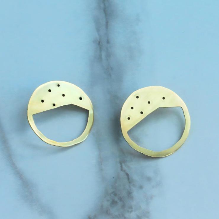 A pair of golden circular earrings in a ceramic surface.