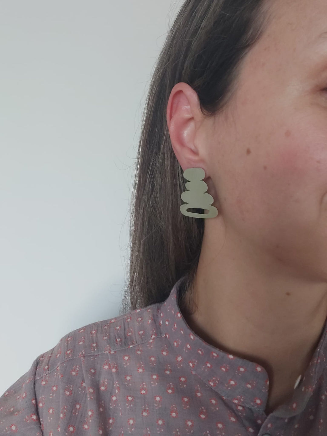 A woman wearing a organic shape earring.