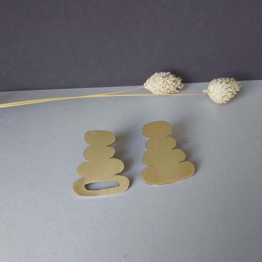 A pair of organic shape earrings in a white surface.