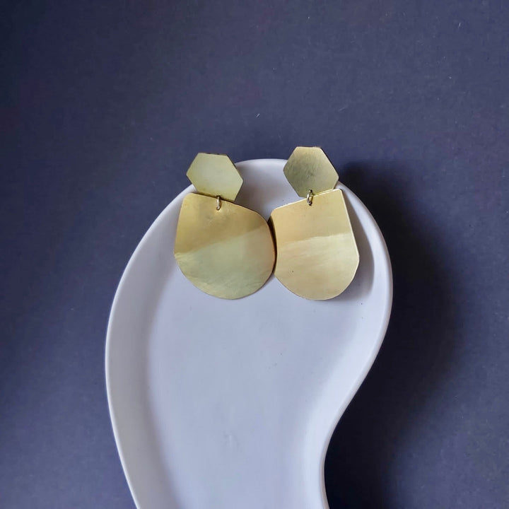 A pair of gold earring in a ceramic plate.