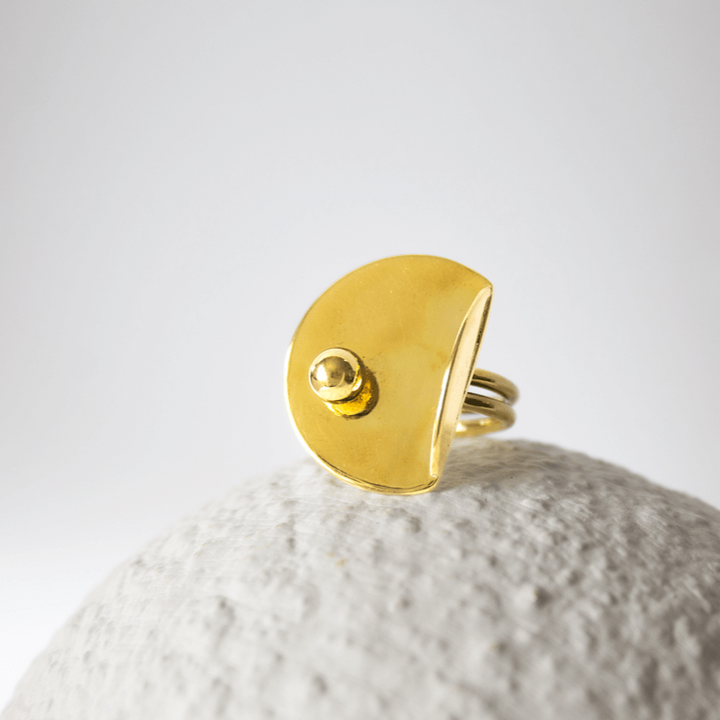 Bold Lines jewellery Gold ring with a small gemstone ball on a textured white surface