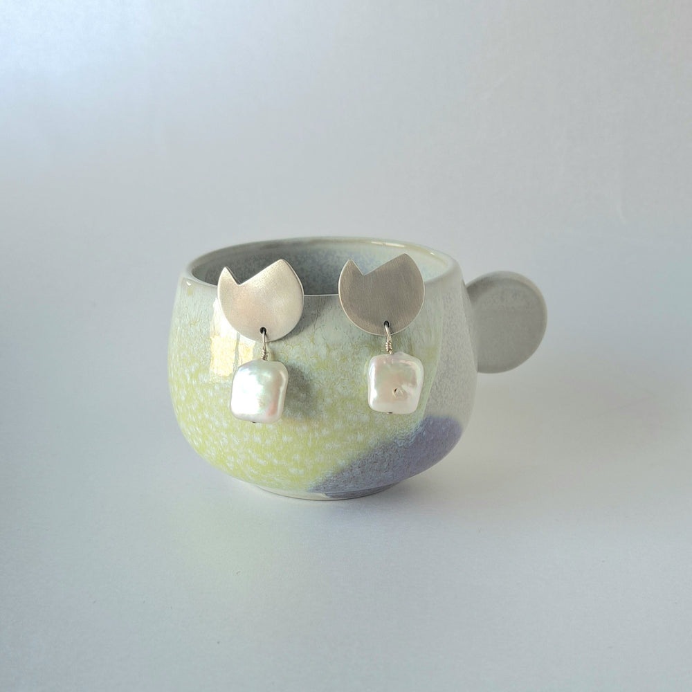 Ceramic bowl with decorative earrings on a light gray background