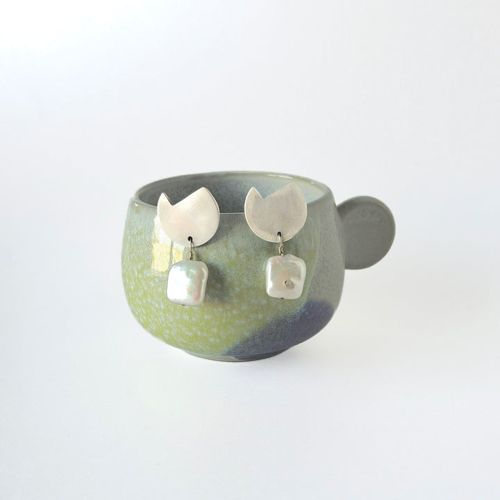 Ceramic bowl with decorative earrings on a light gray background