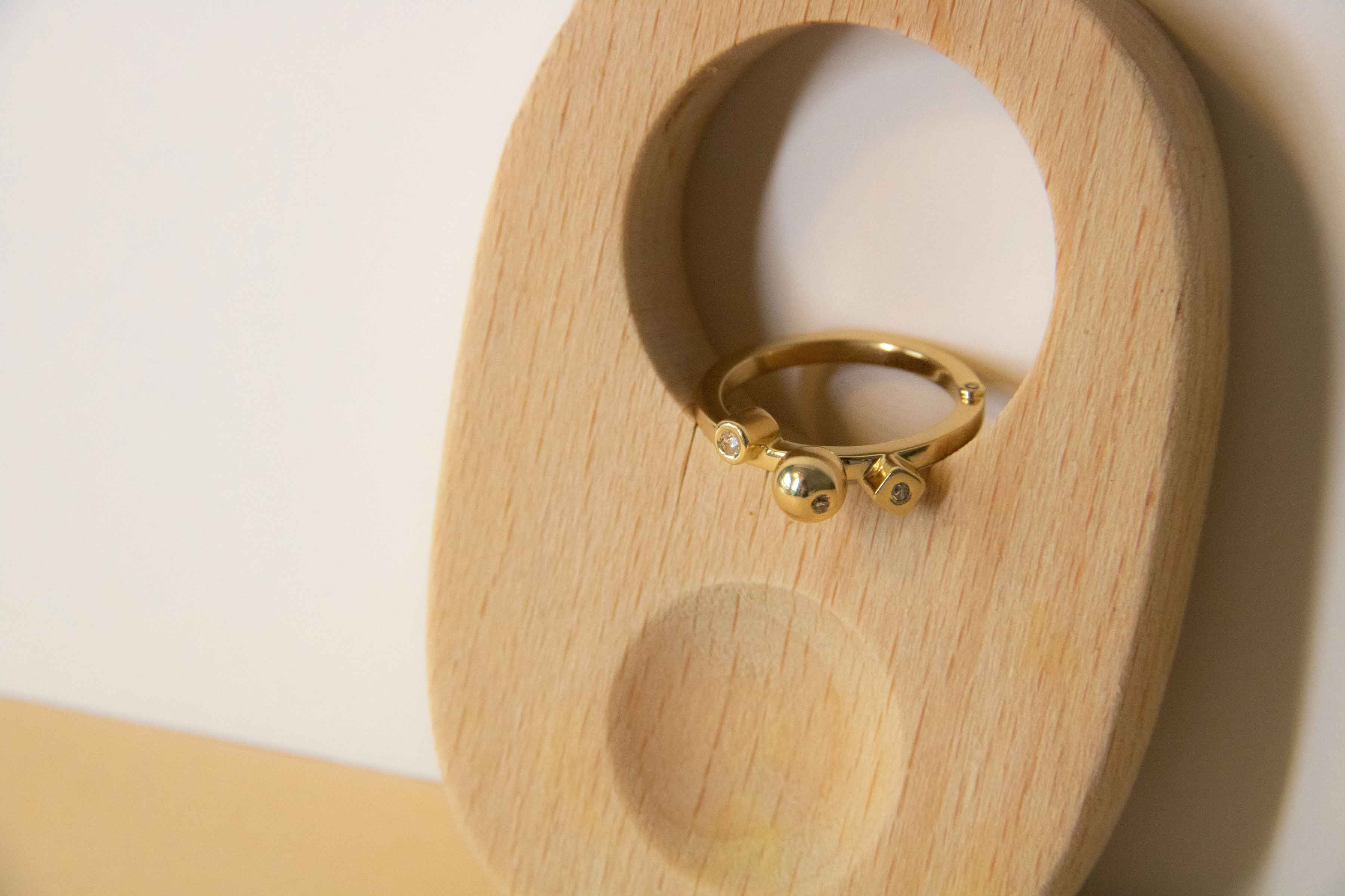 Bespoke geometric and statement ring with diamonds designed by bold lines jewellery shown in a wooden display