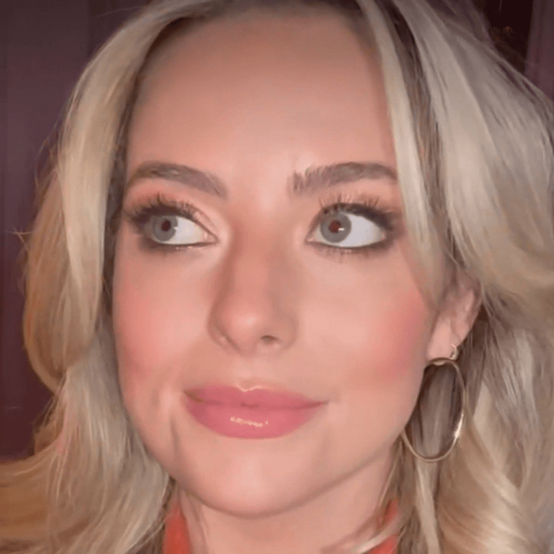 Close-up of a person with blonde hair and an orange top.