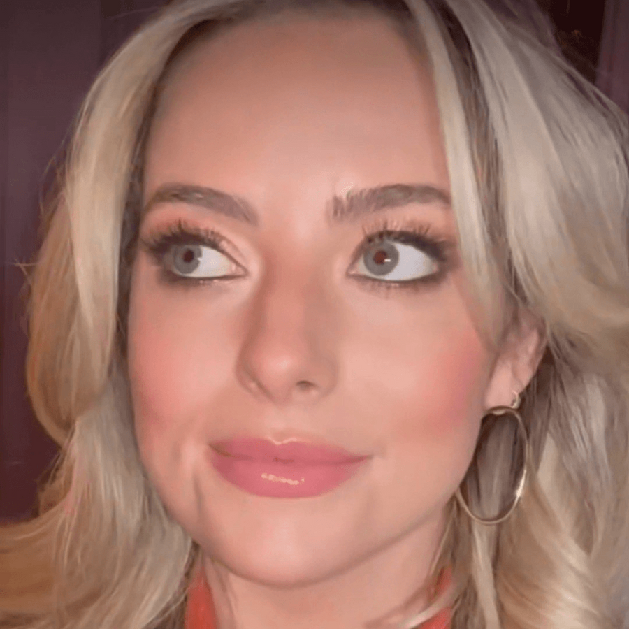 Close-up of a person with blonde hair and an orange top.