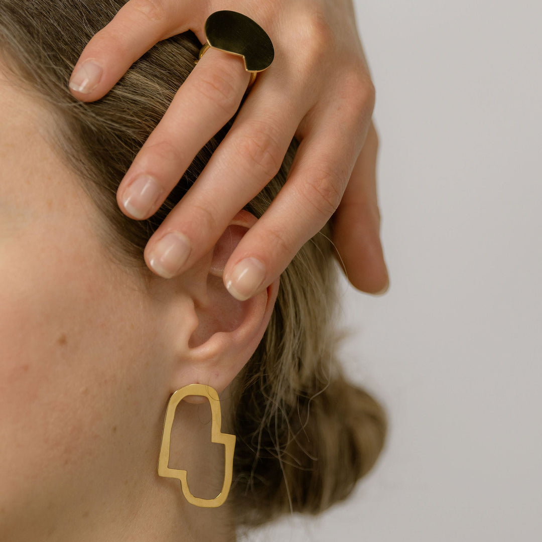woman wearing the bold lines jewellery connection II earrings and hand placed on her head showing the Balance ring.