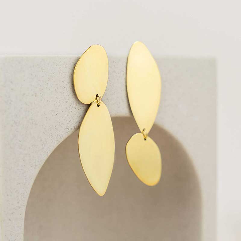Fluidity earrings designed by Bold Lines Jewellery hanging on a geometric circular display.