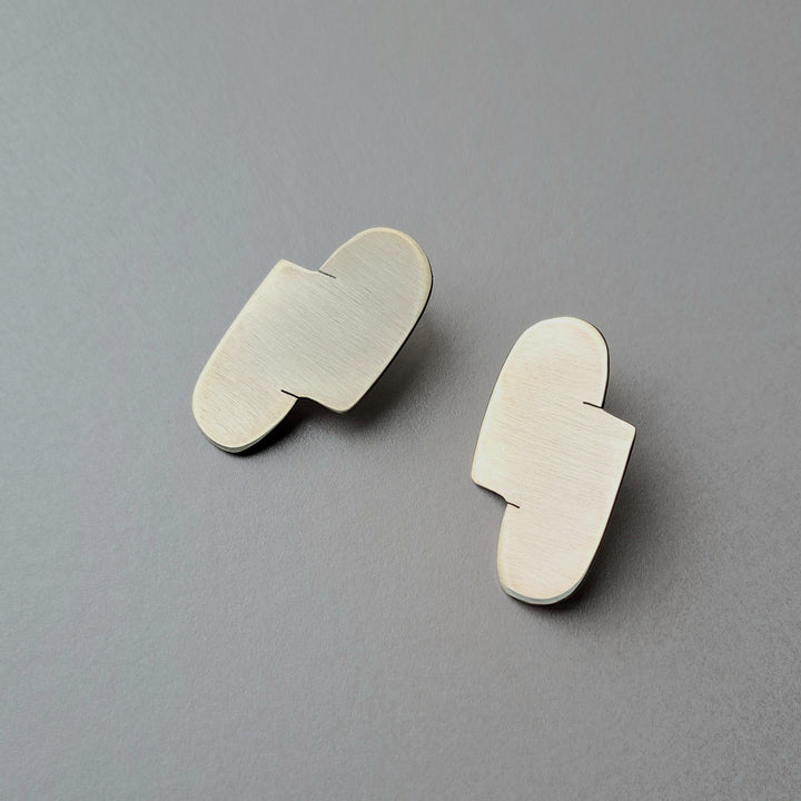 A Pair of abstract silver earrings on a gray background