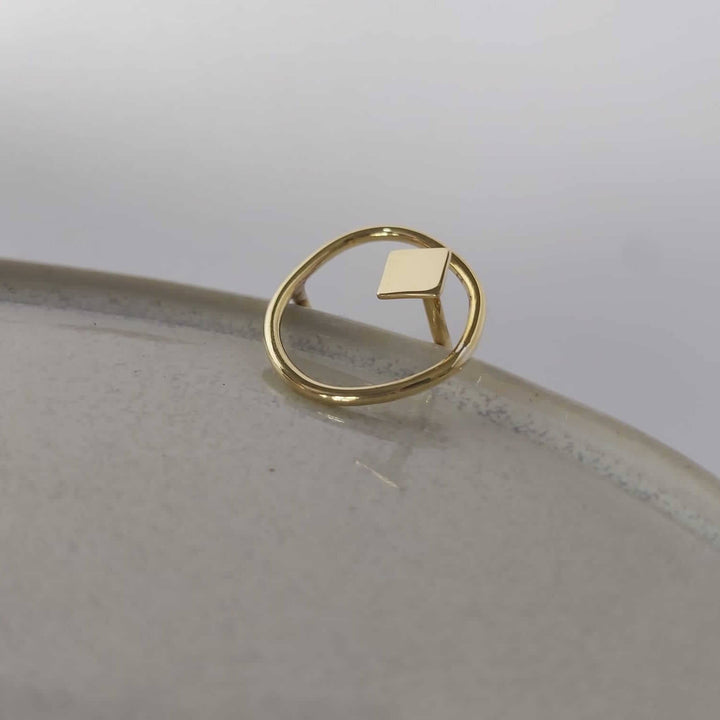 The Bold Lines jewellery Imperfection organic square ring  displayed on a light grey ceramic plate, side view.