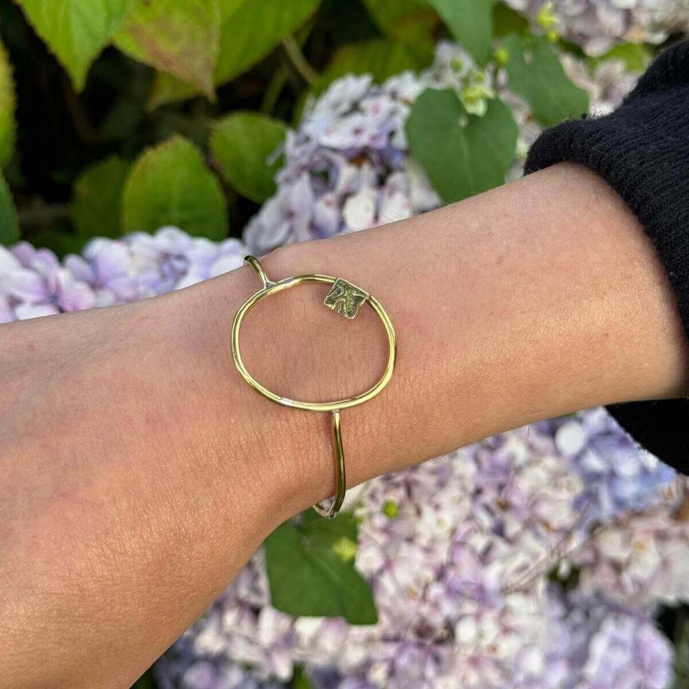 Composition bracelet designed by Julie from Bold Lines Jewellery, worn on a wrist against a backdrop of purple flowers.