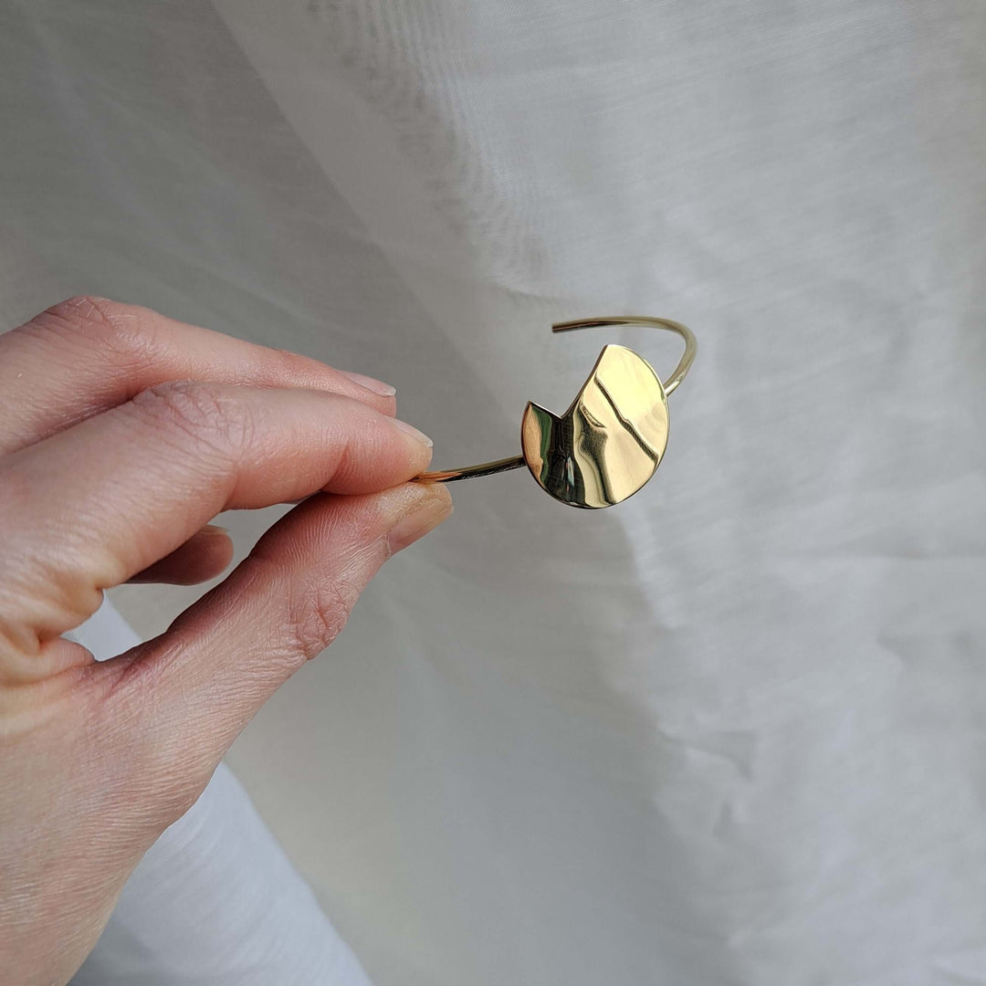 Shot focused on the hand holding the Gold Bold Balance bracelet by Bold Lines Jewellery.