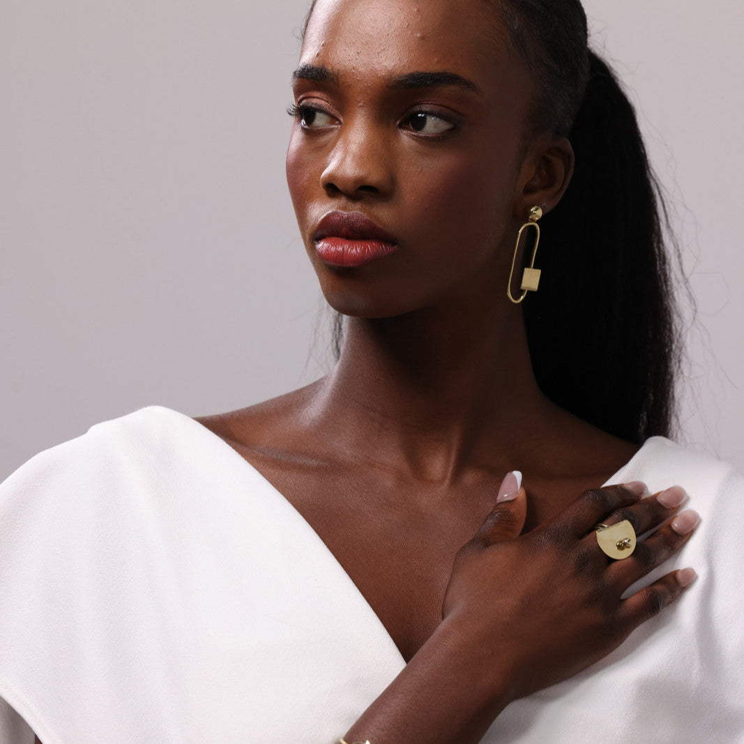Woman wearing gold ring against a plain background