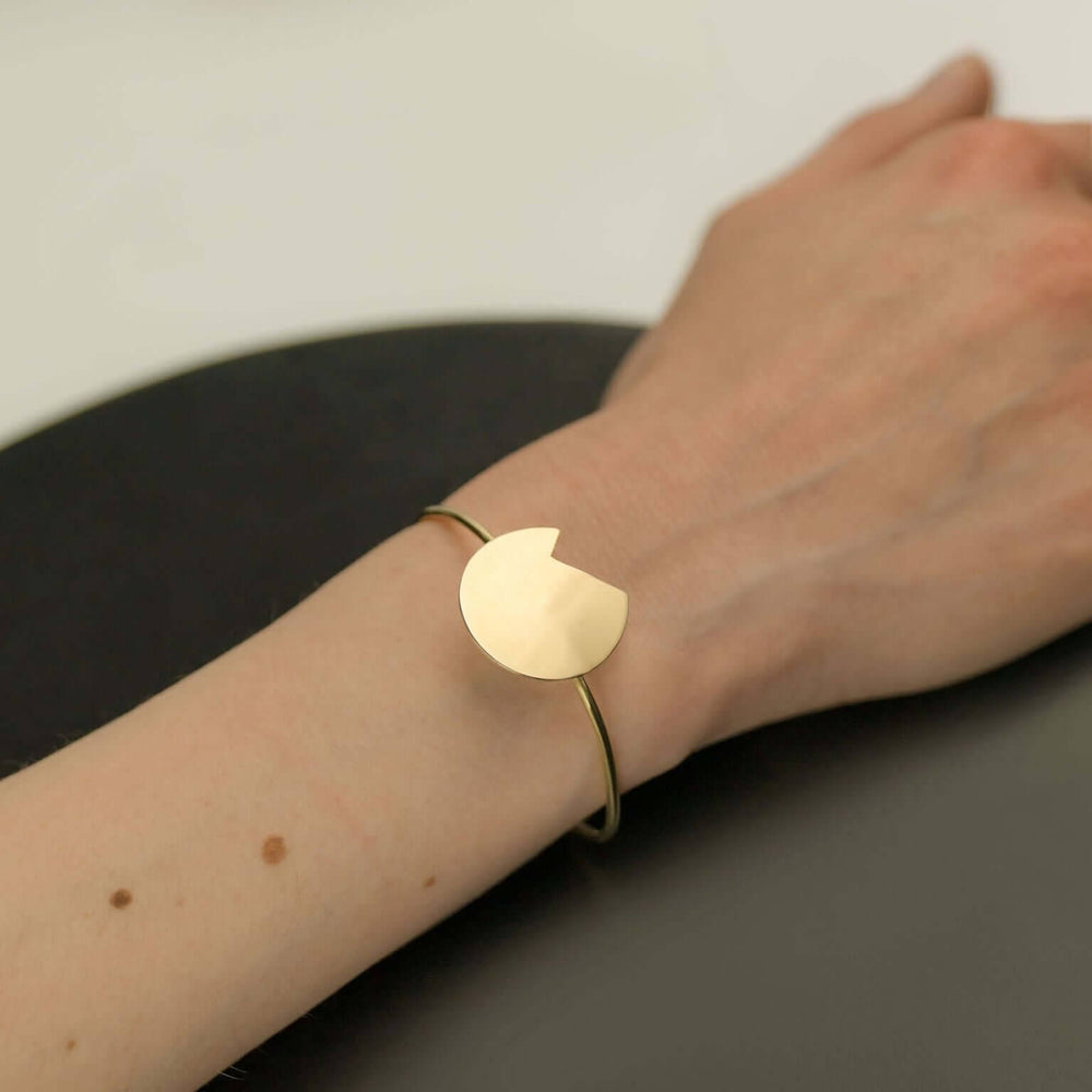 Bold Lines jewellery Balance gold bracelet on a woman's wrist shown on a black background