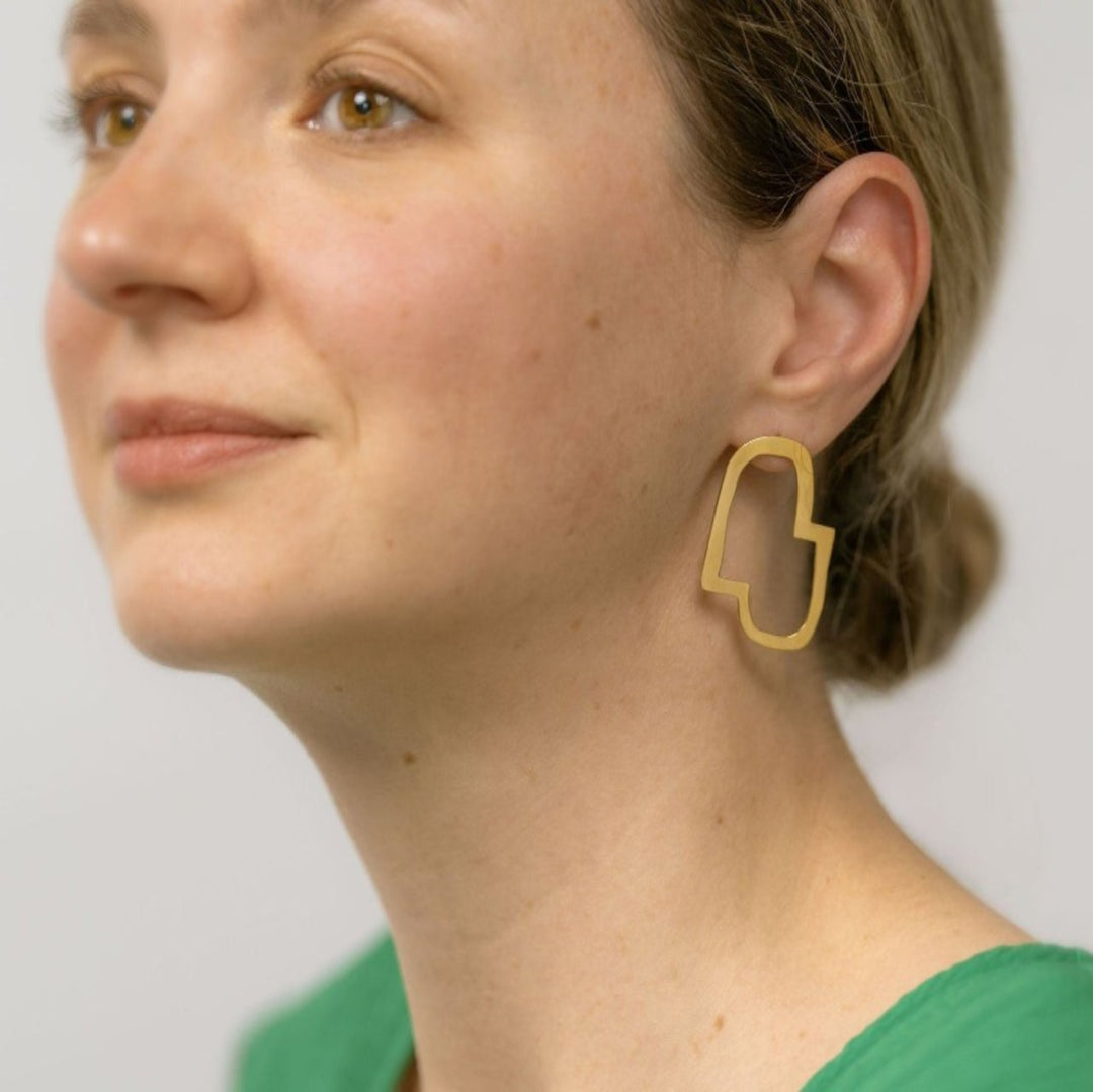 Abstract minimal Connection II stud earrings worn on a model wearing a green dress