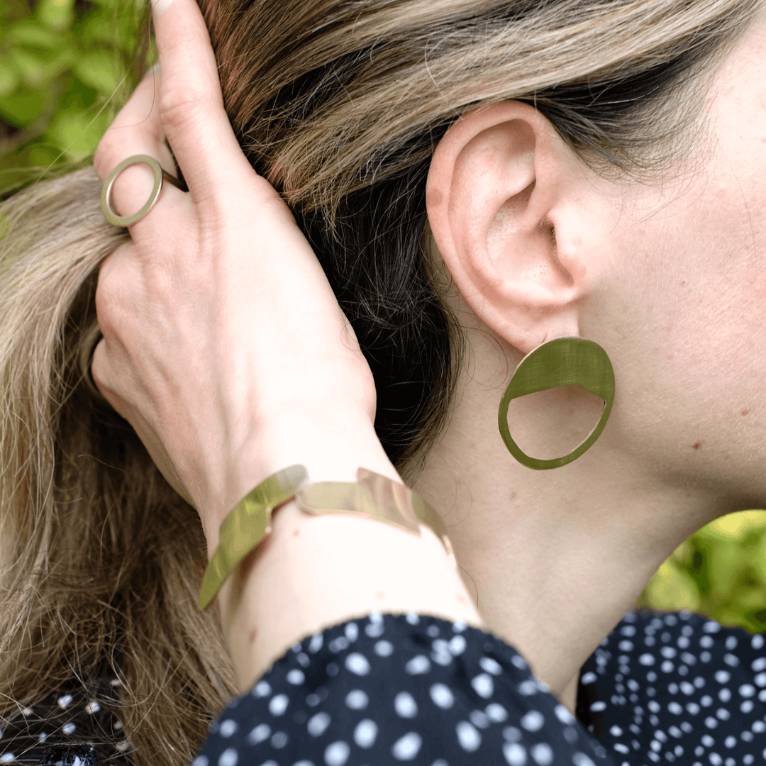 Bold Lines jewellery gold geometric Connection bangle on a woman's wrist paired with galaxy earrings