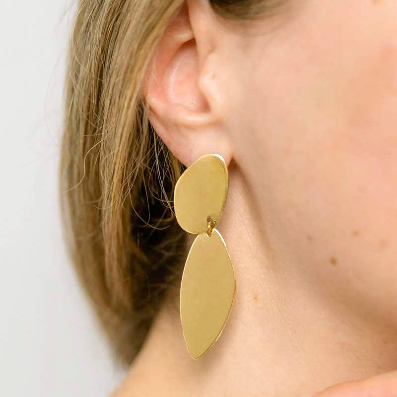 A woman in a white shirt showing the asymmetrical Fluidity earrings by  Bold Lines Jewellery.