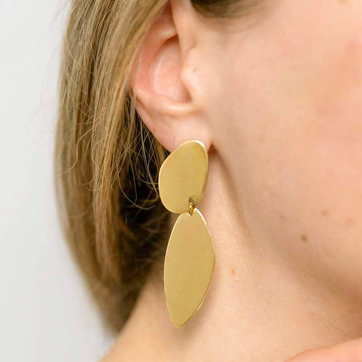A woman in a white shirt showing the asymmetrical Fluidity earrings by  Bold Lines Jewellery.
