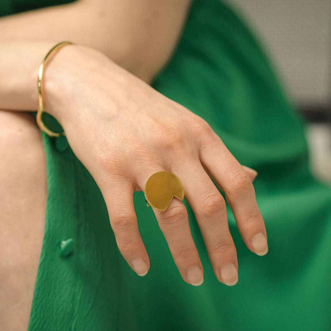 Woman in
green with a hand to her knee showing the Abstract Balance ring