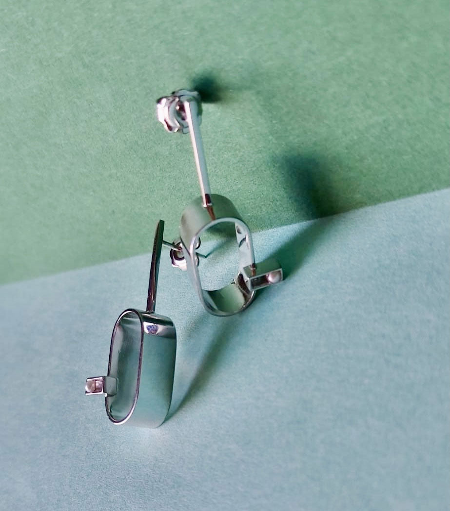 Christine's geometric stud earrings with fresh water pearls designed by Bold Lines jewellery shown in front of a green blue backdrop 