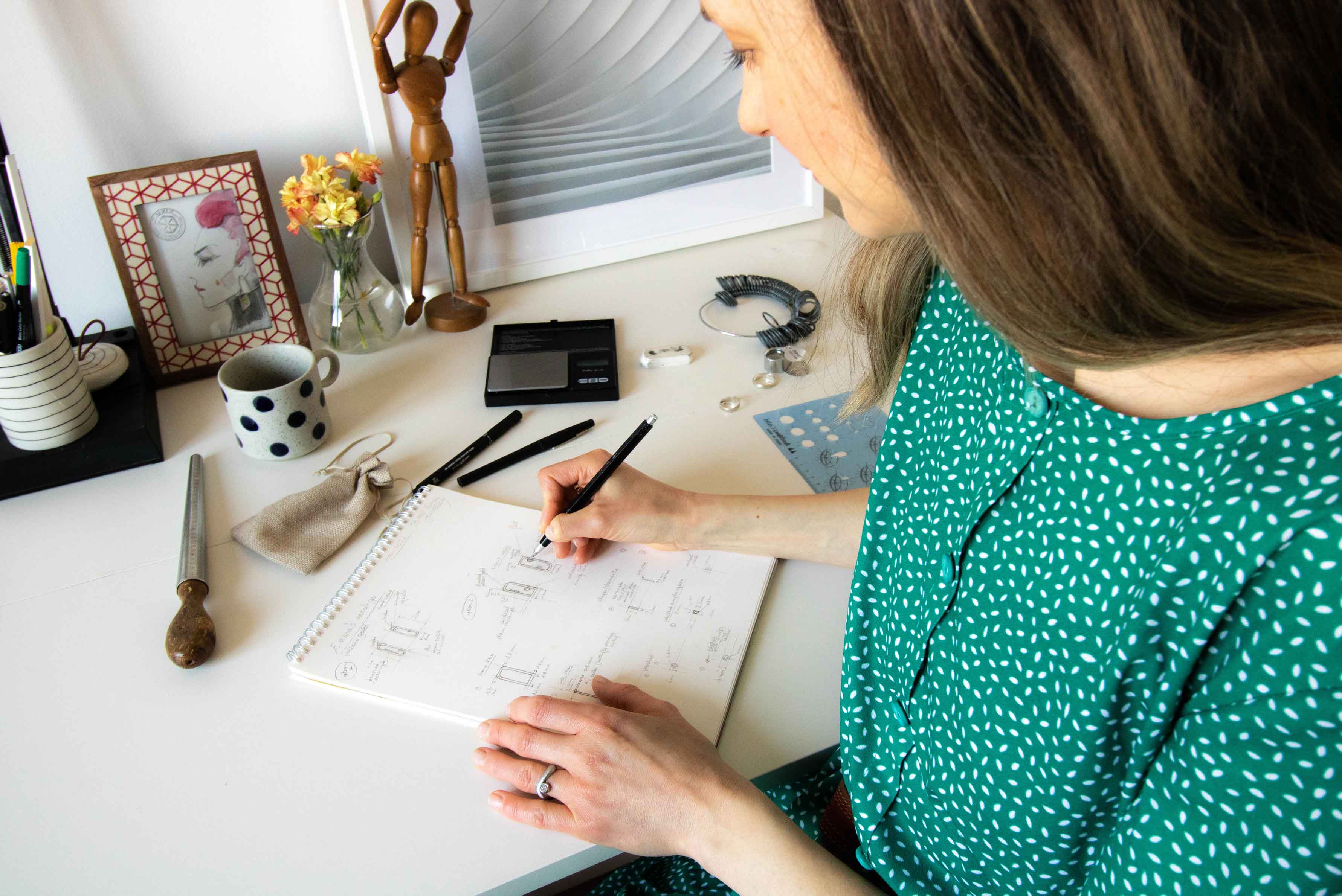 Julie from Bold lines Jewellery sketching  earrings designs at her desk. 