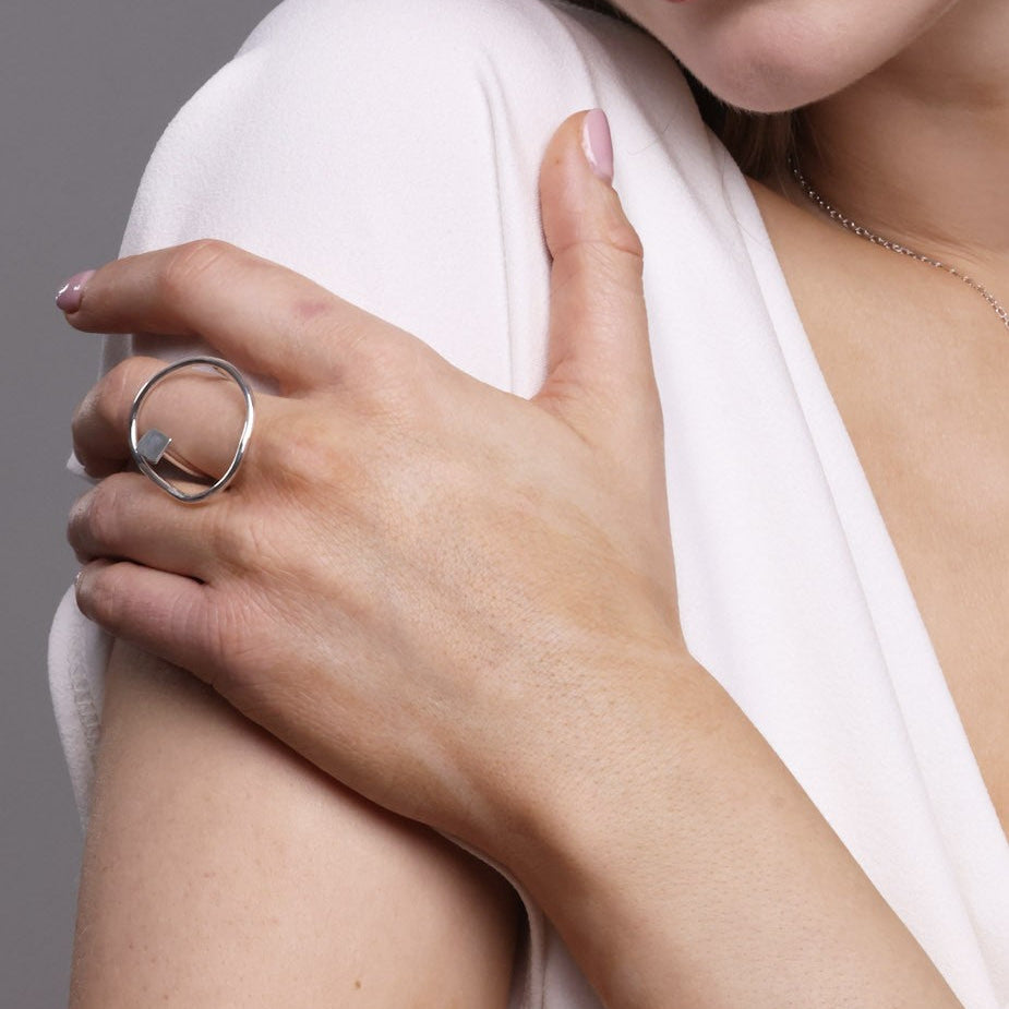 Close-up of a hand wearing a bold lines jewellery silver ring on a neutral background
