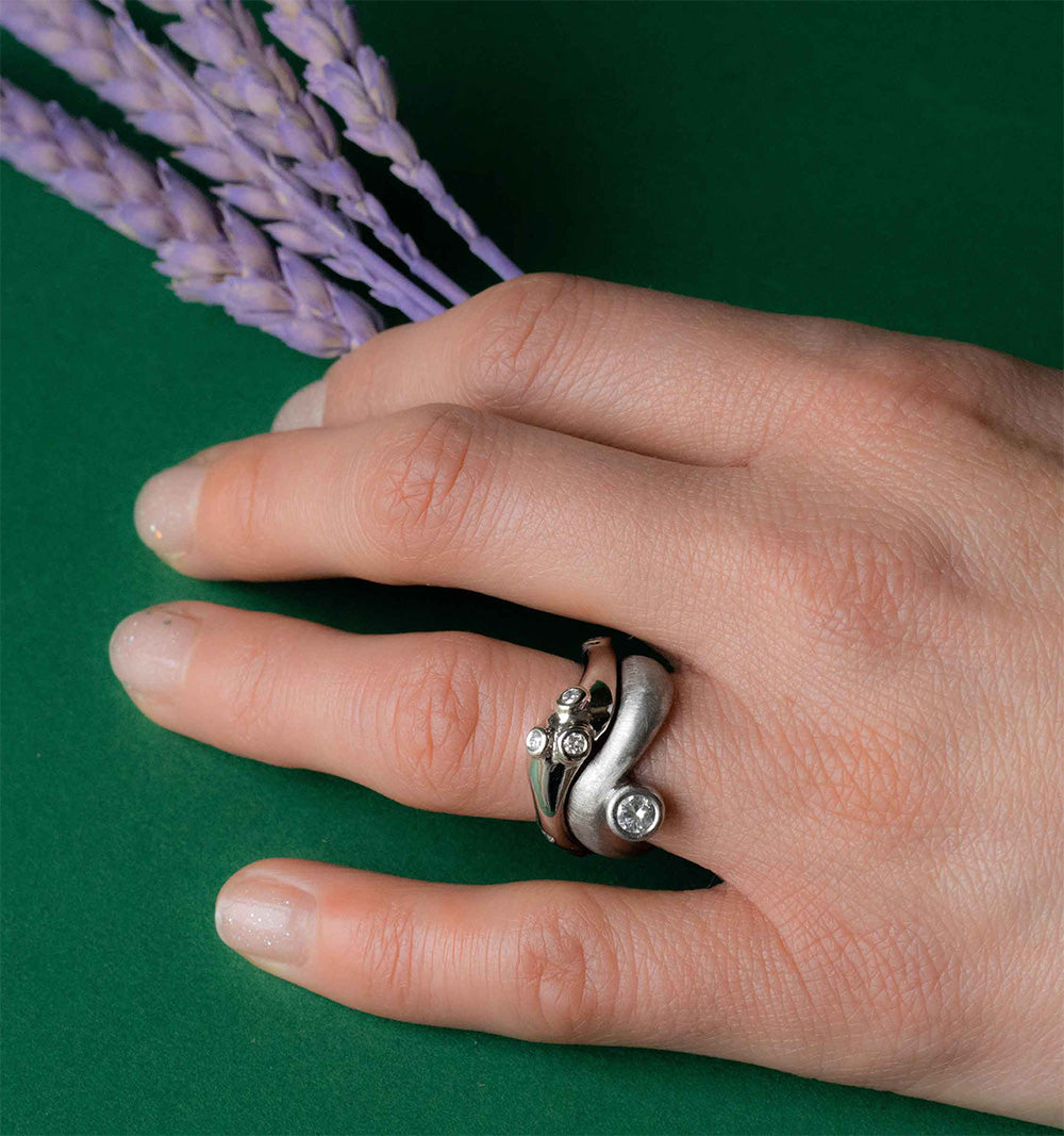 Modern Palladium and diamonds branch remodelled ring by Bold Lines jewellery shown on a hand holding purple wheat on green backdrop