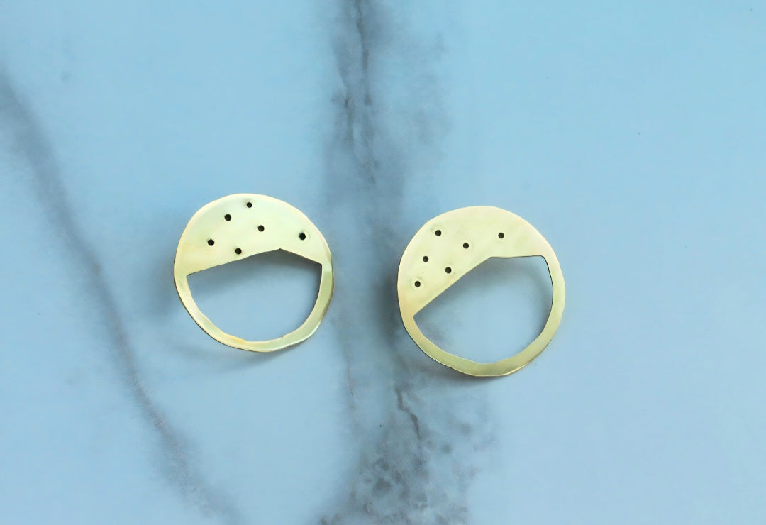 A pair of golden circular earrings in a ceramic surface.