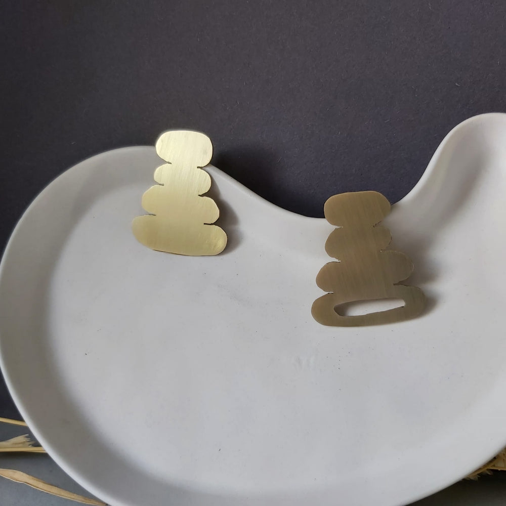 A pair of organic-shaped earrings in a white ceramic plate.