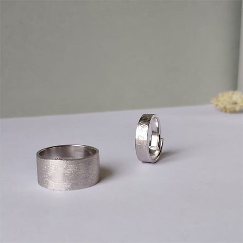 Two modern white gold remodelled wedding bands by Bold Lines jewellery shown on a light grey and green background