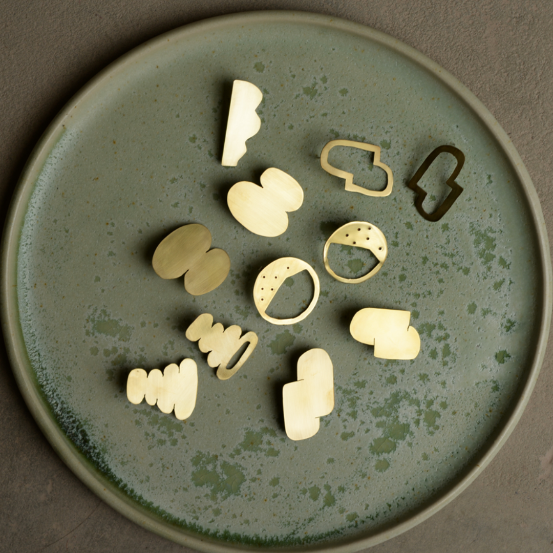 brass graphic jewellery pieces on a pottery plate