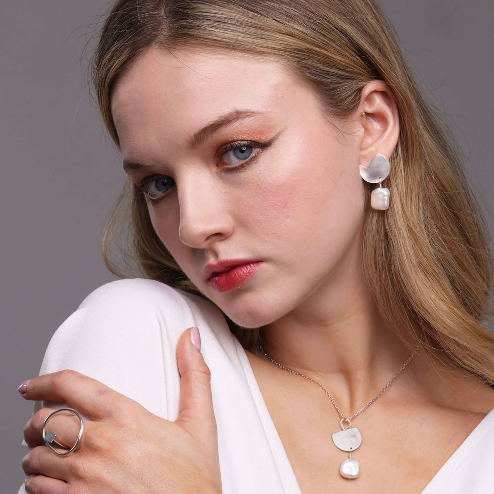 Woman wearing earrings and a necklace with a plain background