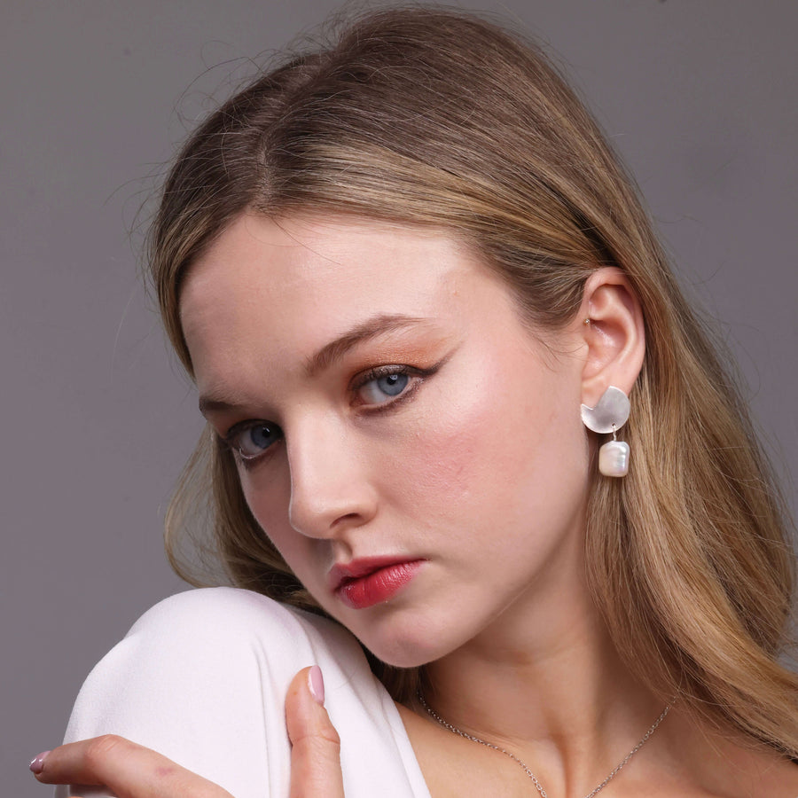 Woman wearing earrings and a necklace with a plain background