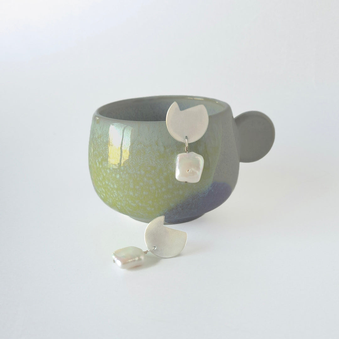 Pair of abstract by bold lines jewelllery earrings displayed on a stand with a white background