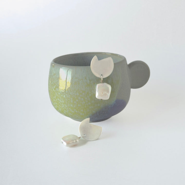 Pair of abstract by bold lines jewelllery earrings displayed on a stand with a white background