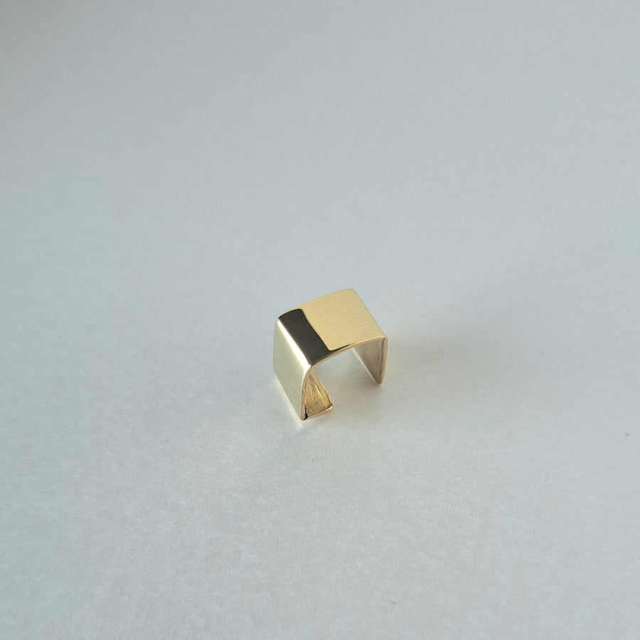 Gold ear ring on a light gray background