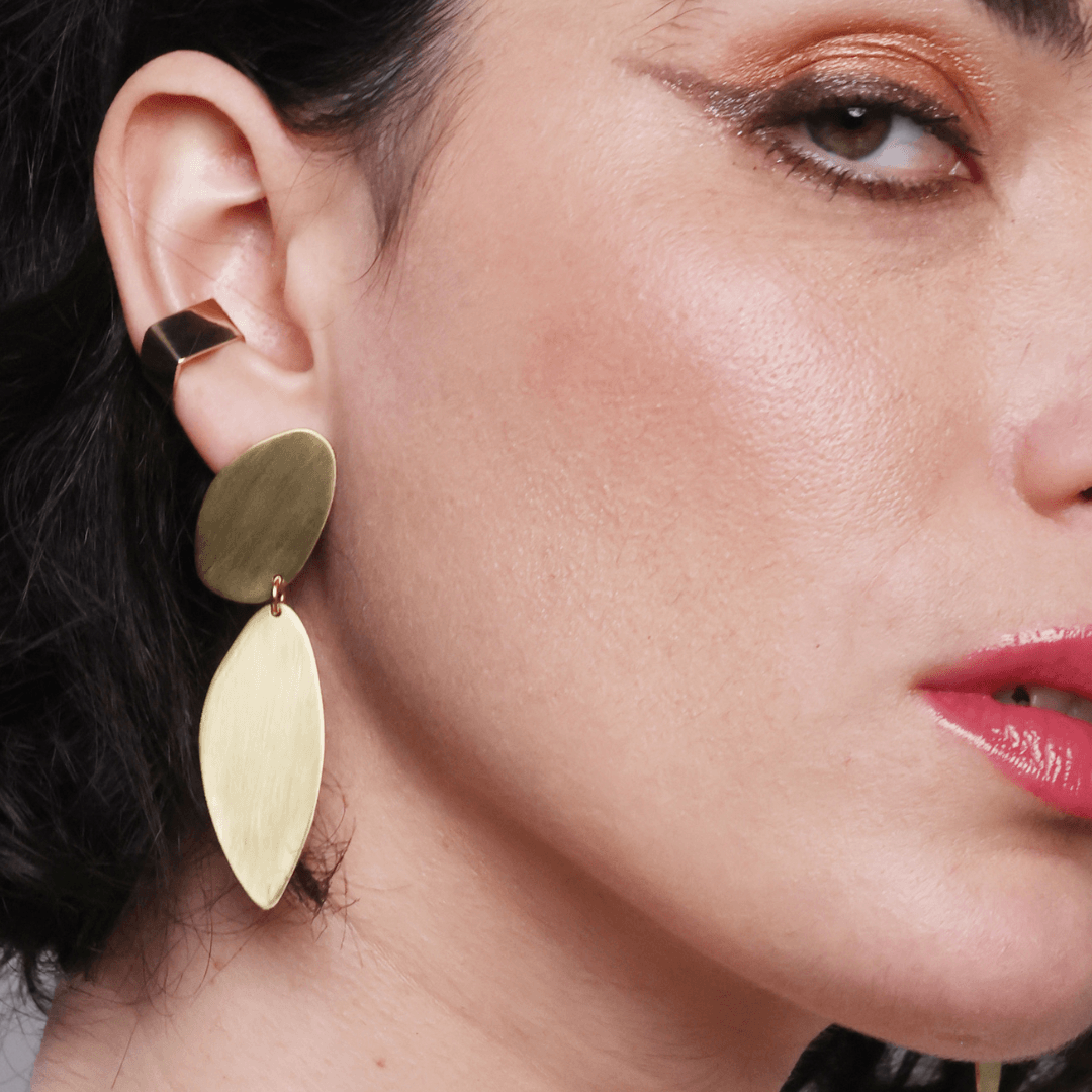 Close-up of a woman wearing gold earrings with a neutral background