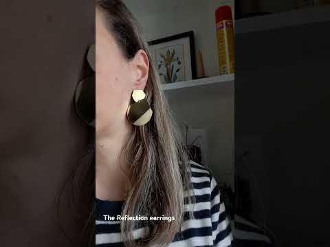 video showing the Reflection  gold dangle  earrings designed by Bold Lines Jewellery on a woman's ear wearing a stripes jumper