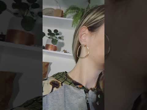 Video of the Imperfection gold hoops earrings worn by a blond woman wearing a silver glitter.