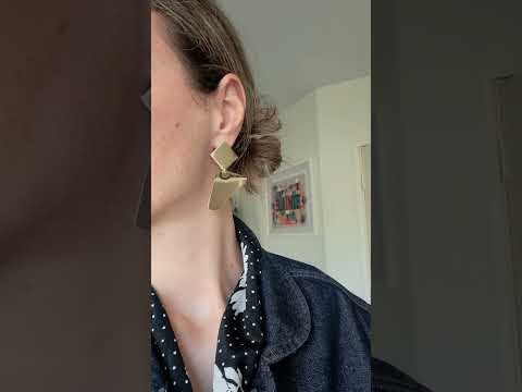 Bold Lines Jewellery Geometrical gold dangle earrings worn on a woman's ear