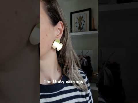 Video of a woman wearing the Unity abstract gold earrings paired with a stripes jumper.