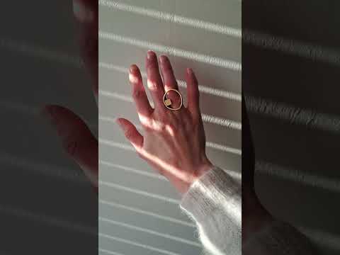 Video of the Imperfection gold ring on a woman's hand in front of a white wall.