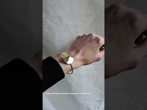 A video of the balance bracelet worn on a model's wrist with a black jumper in front linen fabric.