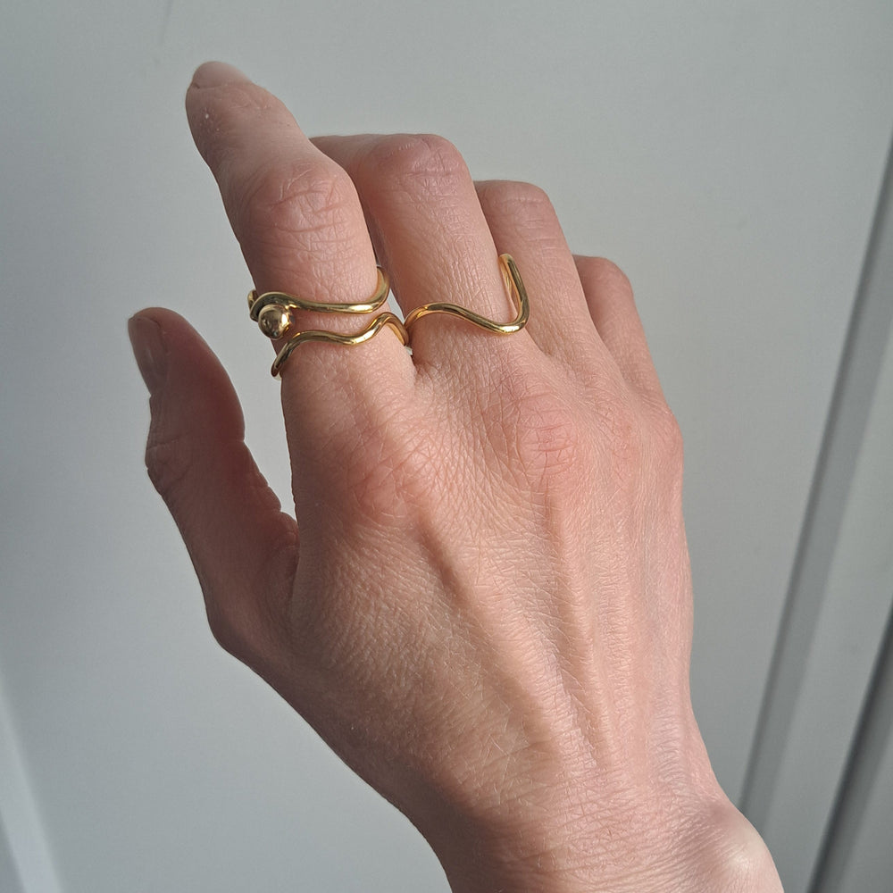 Hand wearing two gold rings on a plain background