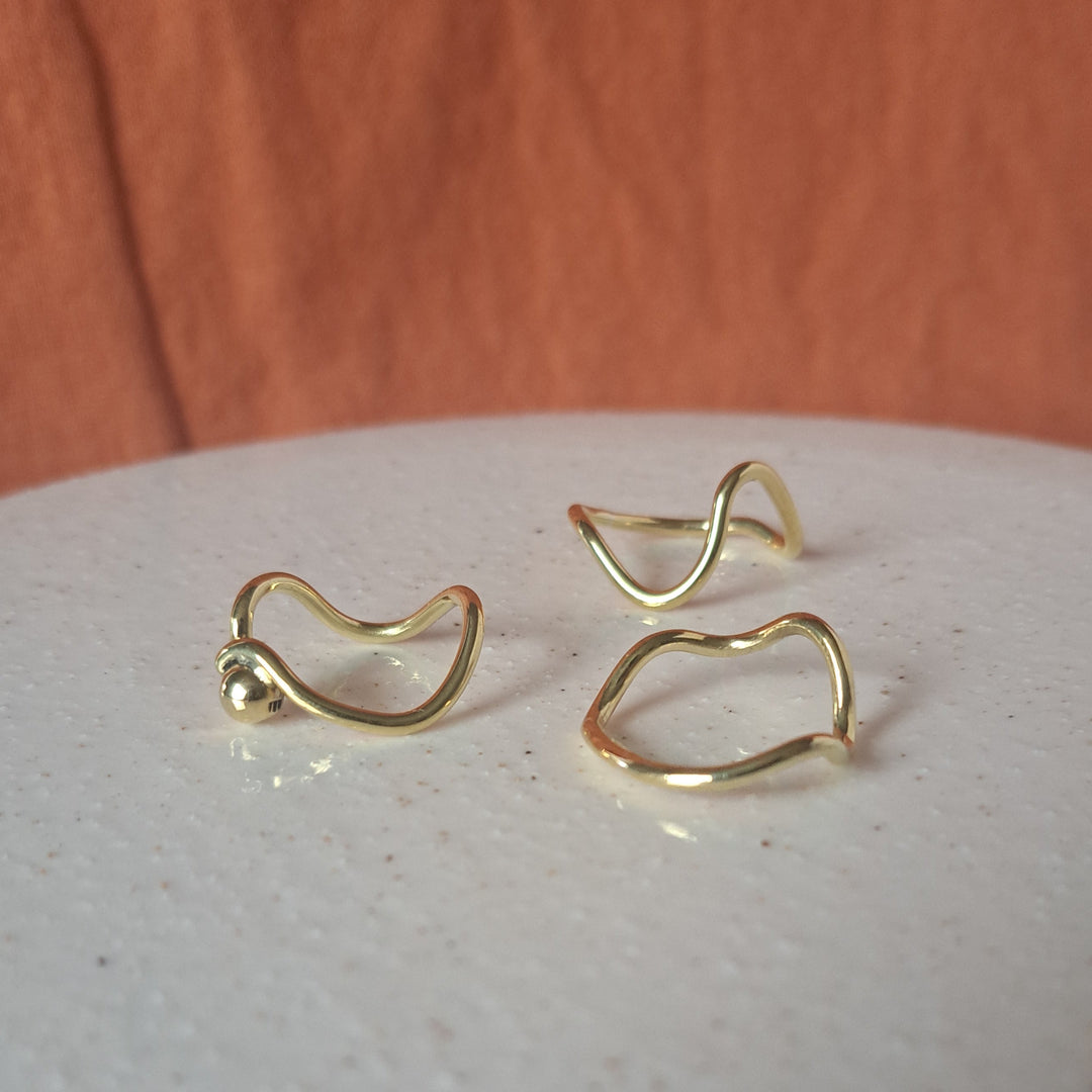 Gold earrings on a textured white surface with a wooden background